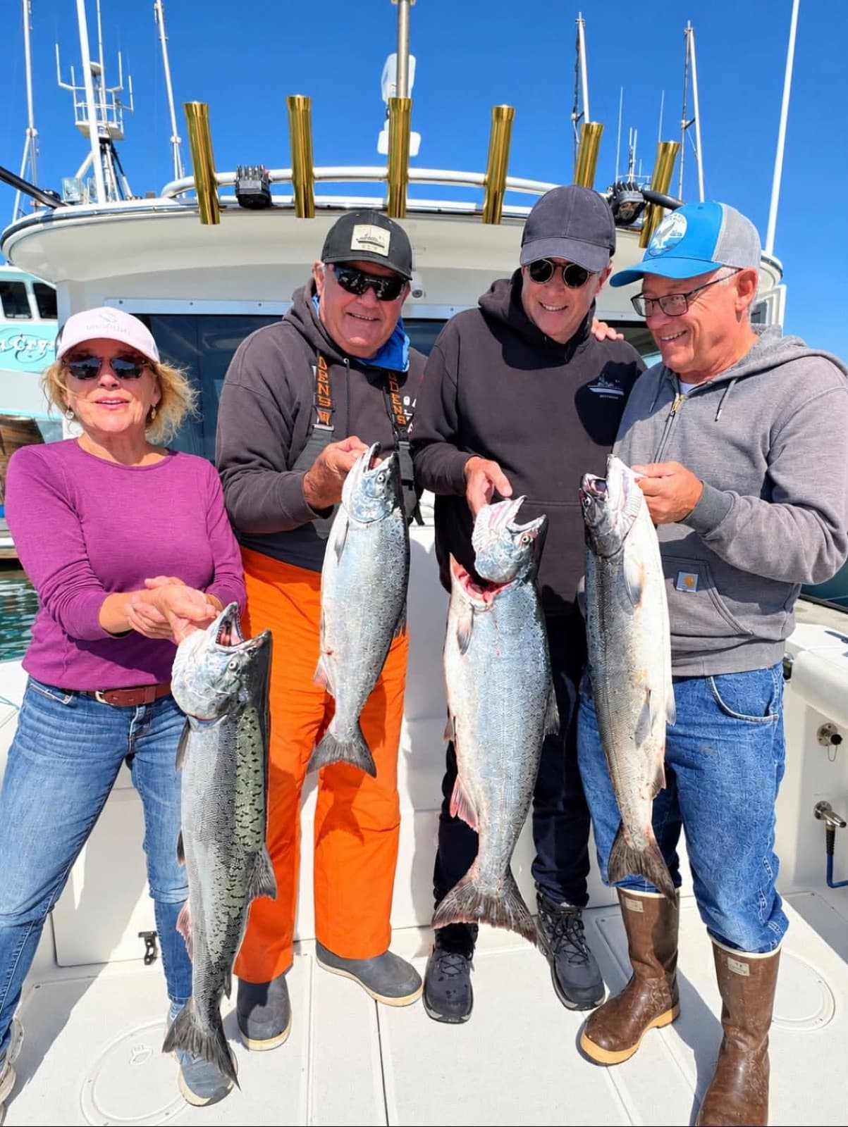 Four guests holding king salmon on the back deck